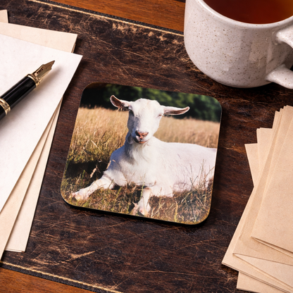 Coaster with a goat design on a wooden desk with a mug of tea and stationery.